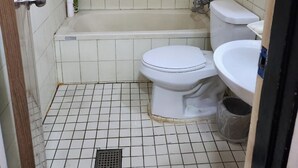 A small, tiled bathroom with a bathtub, two toilets, a sink, and a shower. - Daesungjang (Seoul)