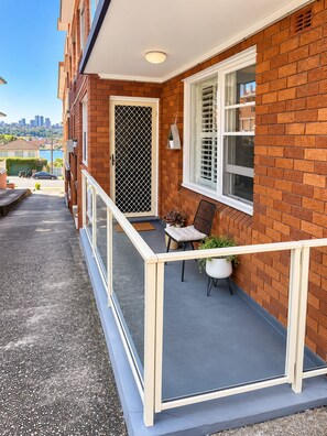 Un immeuble résidentiel doté d’un balcon, d’une porte avec une grille en métal et d’une fenêtre avec des stores.
