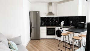 Een moderne keuken met een koelkast, oven, magnetron en barstoelen.