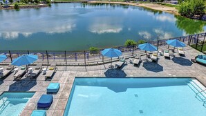 Ein Poolbereich mit Liegestühlen und Sonnenschirmen, mit Blick auf einen See und einem Bergpanorama im Hintergrund.