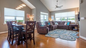 A spacious living room with a dining area, large windows, ceiling fan, and a patterned rug. - Rehoboth Beach Condo w/ Pool Tennis Parking Sleeps 6 (Rehoboth Beach)