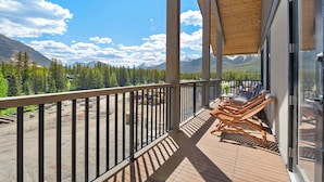 A balcony with wooden flooring, metal railings, and a view of a mountainous landscape. - Spring Creek 3BR Penthouse ~ Wide Mountain Views ~ (Canmore)