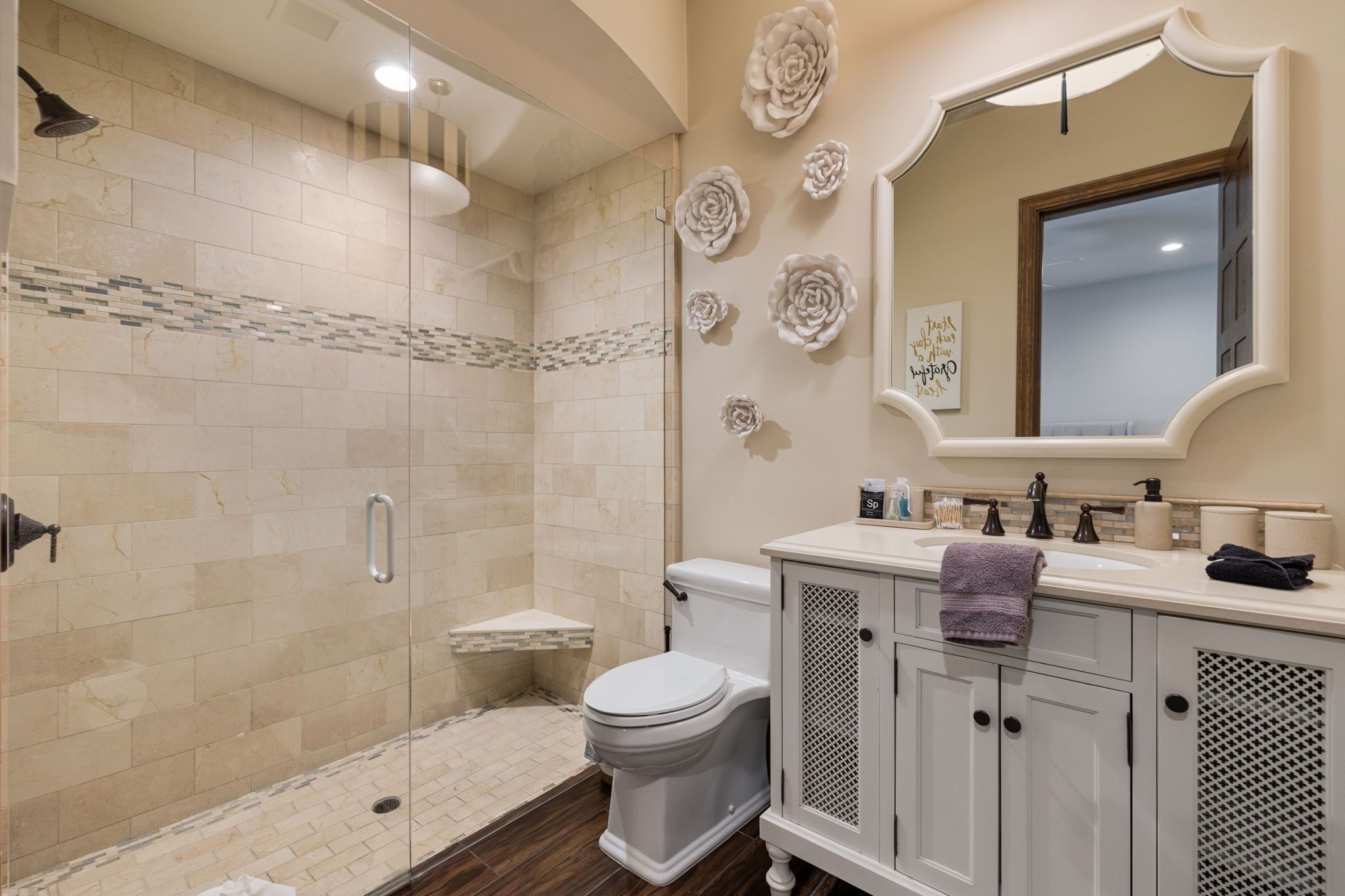 A modern bathroom with a glass-enclosed shower, a toilet, and a vanity with a mirror and sink.