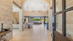 A spacious interior with brick walls, a central seating area, and a view to the outside.