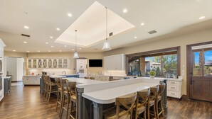 A spacious kitchen with a large island, wooden bar stools, and pendant lighting. - 3.5 Acre compound- 2 pools, tennis, pickleball, basketball, sauna & steam + more (Bermuda Dunes)