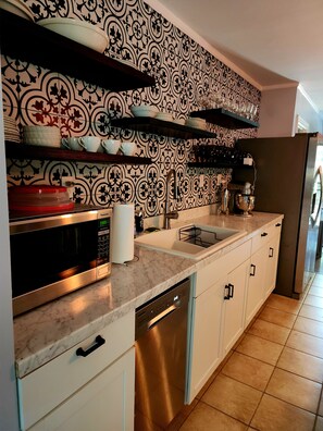 A kitchen with a patterned backsplash, stainless steel appliances, and a dishwasher.
