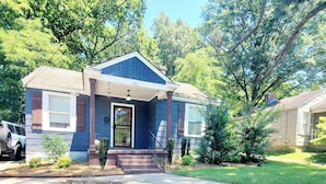 A two-story house with a front porch, a stone retaining wall, and a well-maintained lawn. - Cozy home in quiet neighborhood  (Memphis)