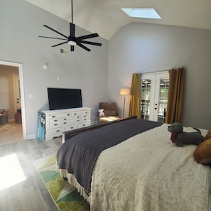 A bedroom with a large bed, a ceiling fan, a TV, a dresser, and a window with curtains. - Cozy home in quiet neighborhood (Memphis)