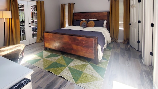 A bedroom with a wooden bed, a ceiling fan, and a view of the outdoors through a window. - Cozy home in quiet neighborhood  (Memphis)
