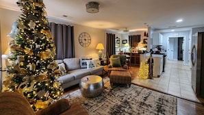 A living room with a Christmas tree, a sofa, a coffee table, and a dining area with a lamp. - Cozy home in quiet neighborhood  (Memphis)