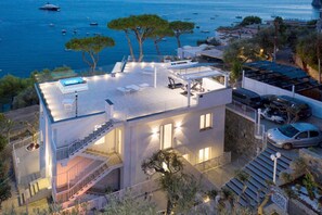 Un edificio moderno con terraza en la azotea, mobiliario exterior y piscina.