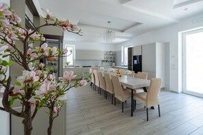 A modern kitchen with white cabinets, a dining area with a table and chairs, and a large window providing natural light.