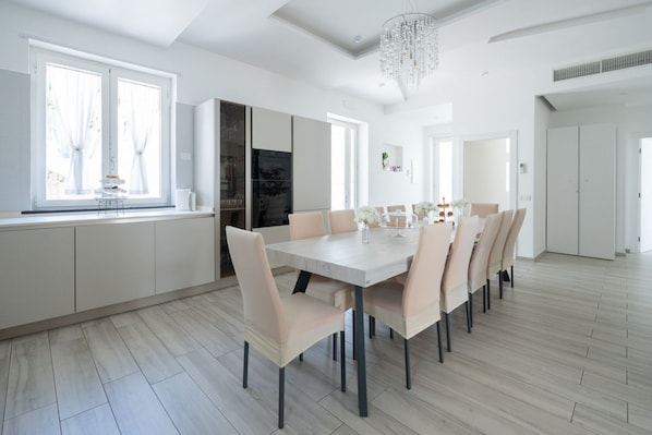 Une cuisine moderne avec un coin repas, de grandes fenêtres et un lustre.