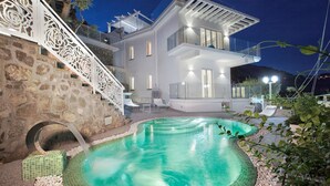 Una casa moderna con piscina, escalones de piedra y un balcón.