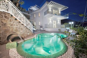 Una casa moderna con piscina, escalones de piedra y un balcón.