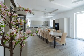 A modern kitchen with white cabinets, a dining area with a table and chairs, and a large window providing natural light.