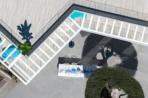 Vue aérienne d’une cour comprenant une piscine, un espace détente et une haie bien entretenue.