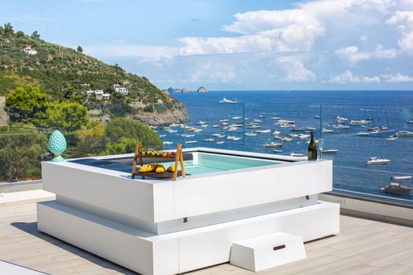 A modern pool area with a view of the sea and boats.