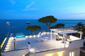 A rooftop terrace with a pool, outdoor seating, and a view of the sea.