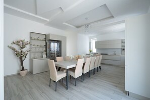 A modern kitchen with white cabinets, a dining area with a table and chairs, and a potted plant.