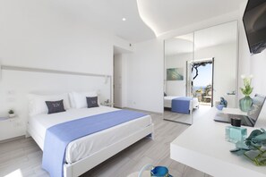 Habitación de hotel moderna con cama, escritorio con una computadora portátil, espejo y vistas al exterior.