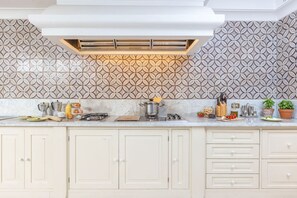 A kitchen with a patterned backsplash, a stove, and various kitchen utensils.