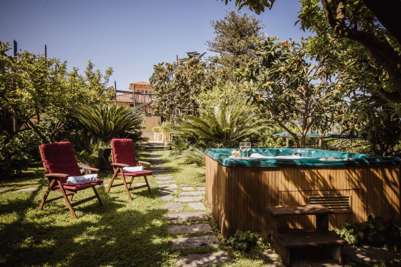 A garden with a hot tub, two red chairs, and a stone pathway.