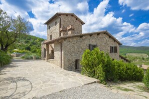 A stone building with a tower, a stone pathway, and greenery.