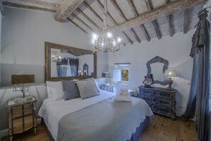 A bedroom with a large bed, a chandelier, a dresser, and a mirror. - MyExclusiveItaly - Chianti's Villa | Vineyard, infinity pool, view (Greve in Chianti)