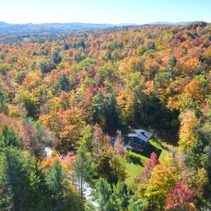 A house surrounded by a forest with autumn foliage.
