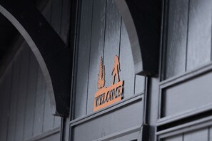 A welcome sign with a silhouette of a person walking, mounted on a dark wooden structure.