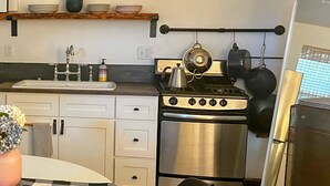 A compact kitchen with white cabinets, a stainless steel stove, and a refrigerator. - Private Cozy Garden Studio Retreat - Near Downtown, Gardens & Forest Park (Portland)