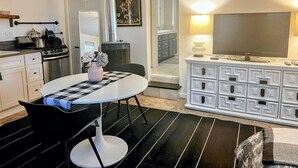 A compact kitchen with modern appliances, a dining area with a round table and chairs, and a living area with a TV and entertainment center. - Private Cozy Garden Studio Retreat - Near Downtown, Gardens & Forest Park (Portland)