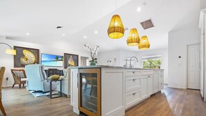 A spacious kitchen with white cabinetry, a large island, and pendant lighting.