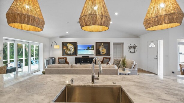 A spacious living area with a large kitchen island, a sofa set, and a television.