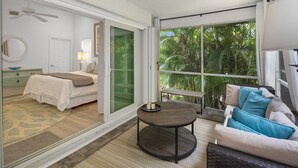 A bedroom with a bed, a bedside table, a chair, and a view of the outdoors through a sliding glass door.