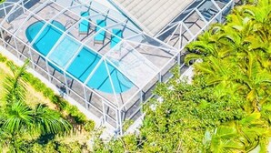 A modern building with a glass-enclosed swimming pool and a covered patio area.