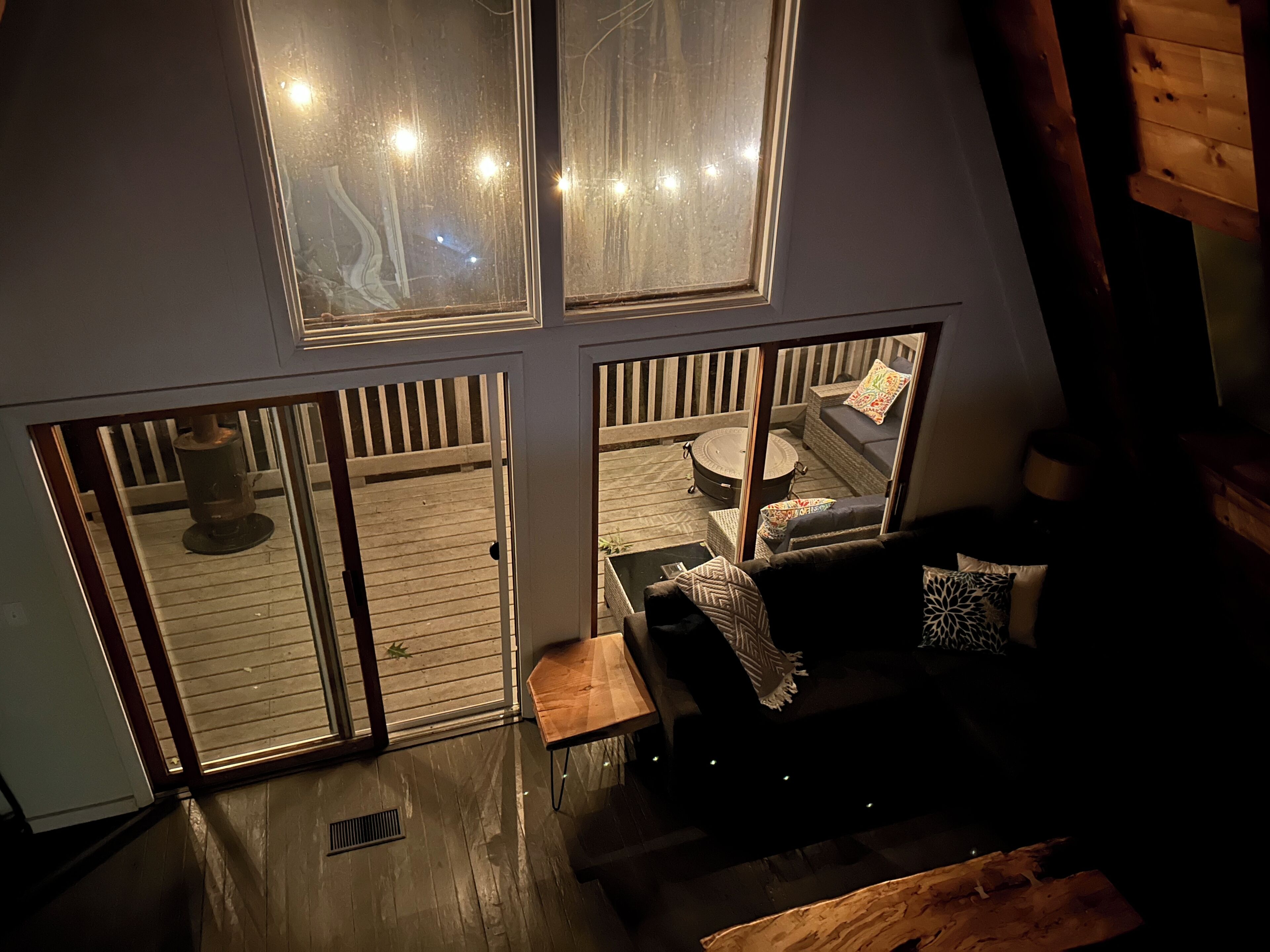 A cozy interior with a wooden deck, a fireplace, and a seating area with cushions. - The ‘A’mazing Escape! Beaches, hiking trails, & great fall color tour location! (Manistee)
