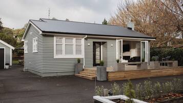 Enjoy a peaceful retreat on this single-story home's porch, complete with a cozy seating area and lush garden views.