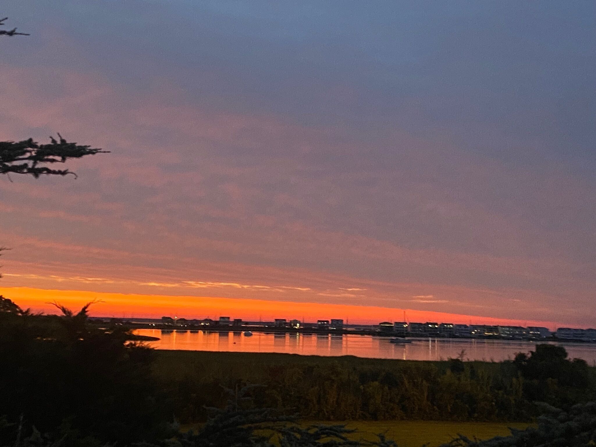 A sunset over a body of water with a distant city skyline.