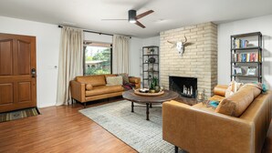 A living room with a brick fireplace, leather sofas, a coffee table, and a bookshelf.