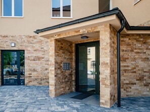 A building entrance with a stone facade, a glass door, and a small overhang above the door. - Nice apartment for 5 people with WIFI, TV, balcony and panoramic view (Ostrov)