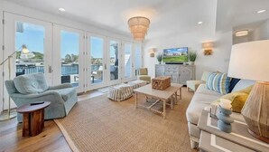 A spacious living room with a large window, a sofa, a coffee table, and a television. - Gentle Slope Lakefront beautiful sunset,6Bds,4.5Bas, kayaks,paddleboards,firepit (Moneta)