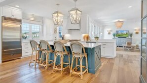 A modern kitchen with white cabinetry, a central island with bar stools, and pendant lighting. - Gentle Slope Lakefront beautiful sunset,6Bds,4.5Bas, kayaks,paddleboards,firepit (Moneta)