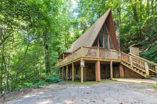 Eine Holzhütte mit einer Holzterrasse und Treppe, umgeben von dichtem Wald.
