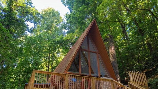 Una cabaña de madera con balcón, rodeada de un bosque denso.