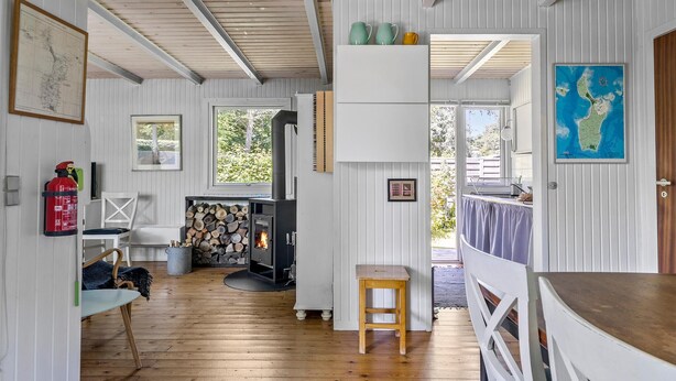 Ein gemütliches Blockhaus-Interieur mit Holzboden, Kamin, Essbereich und Blick ins Freie.