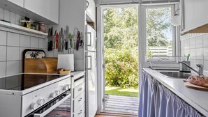 Eine moderne Küche mit weißen Schränken, einer Holz Arbeitsplatte und Blick auf einen Garten durch eine offene Tür.