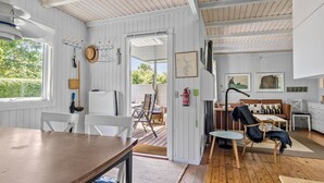 Ein rustikales Blockhaus-Interieur mit einem Holzesstisch, einer Couch und einem Feuerlöscher an der Wand.