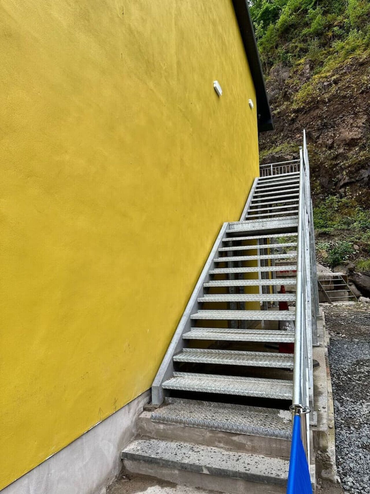 A set of concrete stairs leading up to a yellow building.